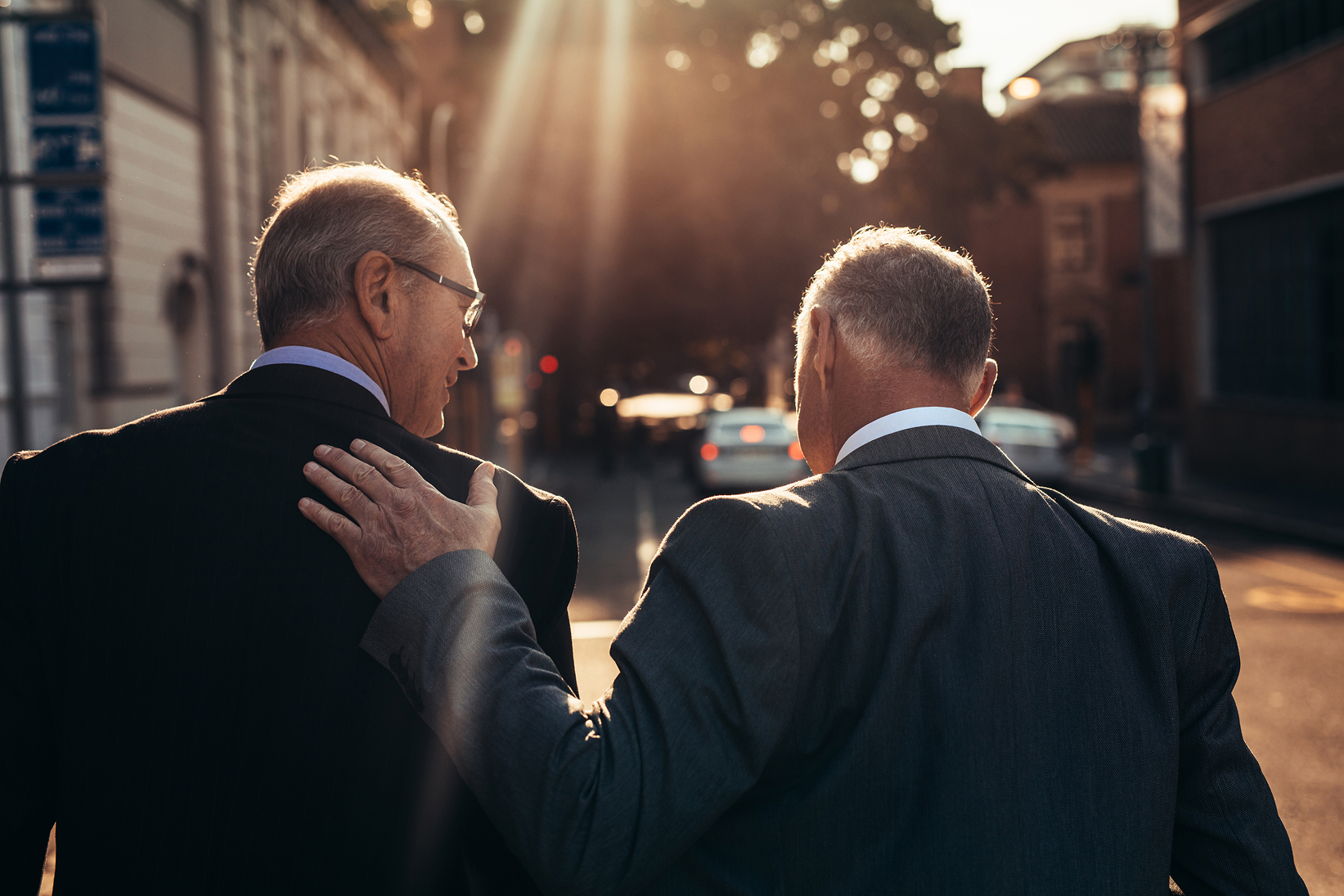 An older man patting another on his shoulder
